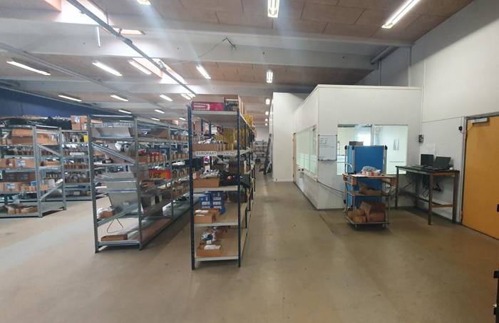 Før: Ujævnt lys og mørke zoner mellem reolerne.